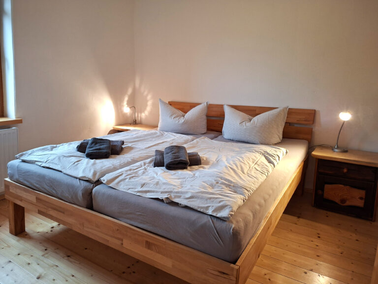 Das Bild zeigt das Doppelbett im Schlafzimmer in der Erdgeschoss Ferienwohnung in der Luxusboofe in Königstein