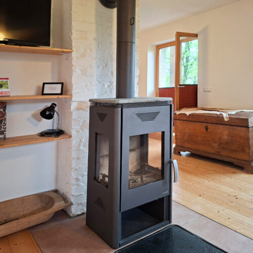 Das Bild zeigt das Wohnzimmer mit Kamin & TV in der Erdgeschoss Ferienwohnung in der Luxusboofe in Königstein