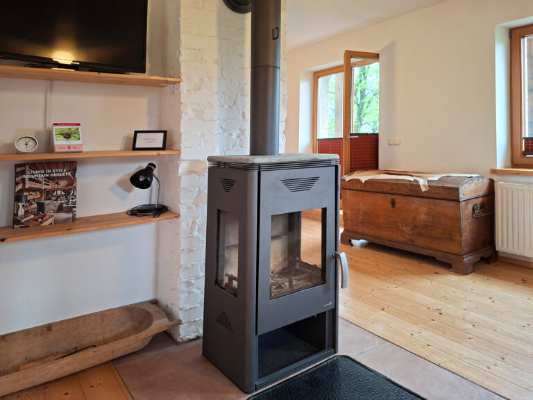 Das Bild zeigt das Wohnzimmer mit Kamin & TV in der Erdgeschoss Ferienwohnung in der Luxusboofe in Königstein